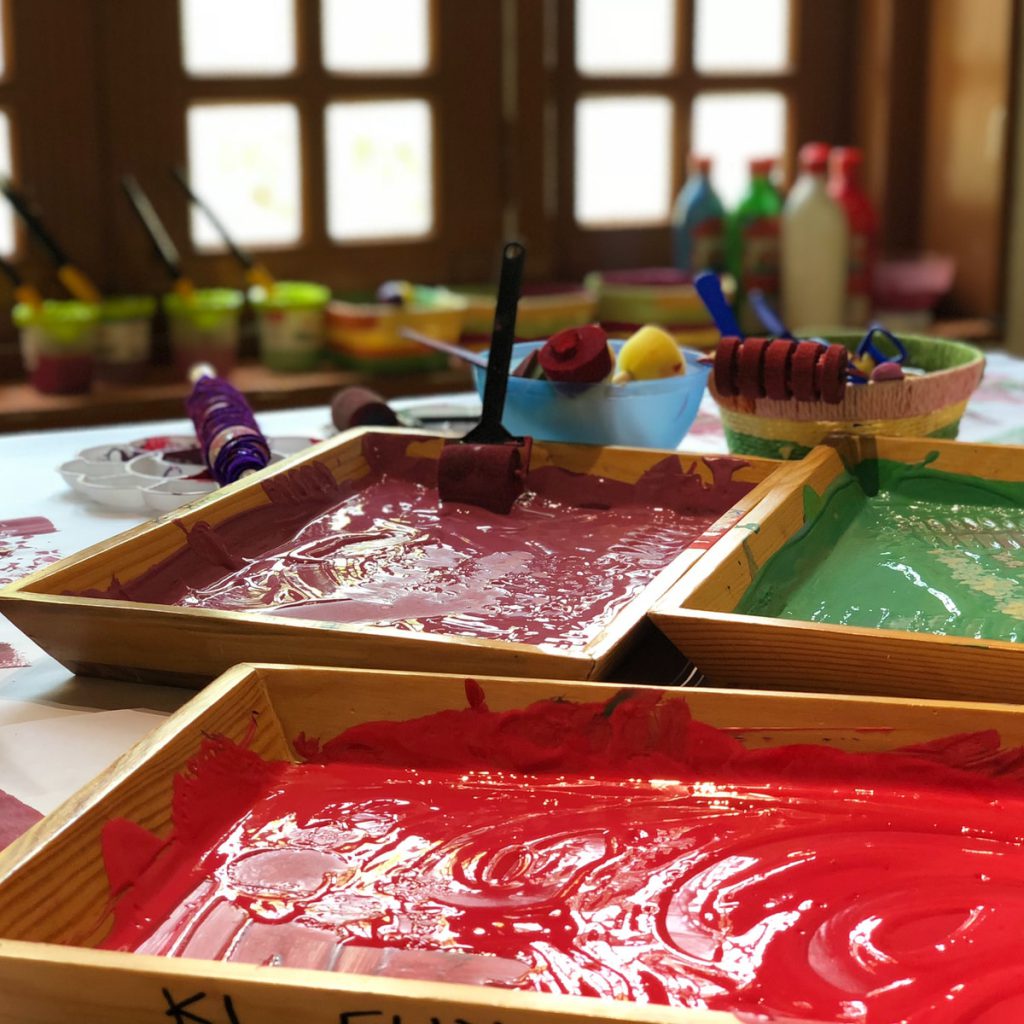 assorted paints in brown wooden trays on table